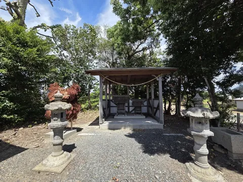 境内に建つ切妻屋根の社殿を正面やや左から見た様子。左右に石灯籠が並び、藁の飾り物が置かれている。