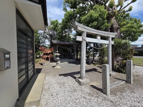 公会堂の軒先から鳥居と社殿方向を見た参道の様子。左手前に藁の飾り物と石灯籠が見える。