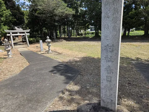 社号標の近景。奥に石灯籠と鳥居、社殿が見える境内の様子。