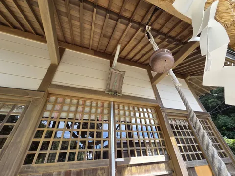 拝殿の軒下に掲げられた「王子神社」の扁額と大きな鈴を、しめ縄越しに見上げた様子。