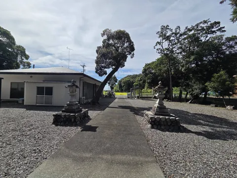 参道の全景。両脇に石灯籠が立ち、左手に境内の建物、正面奥に社叢が見える。