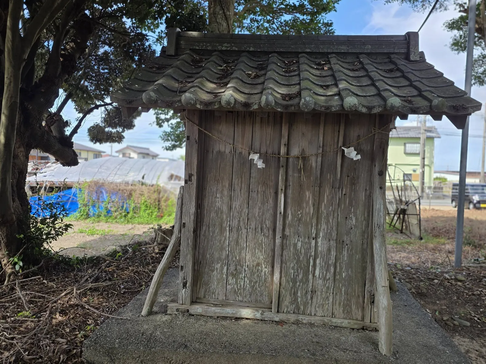 境内社（祠）の正面。瓦葺きの屋根と木製の扉、しめ縄と紙垂が見える。