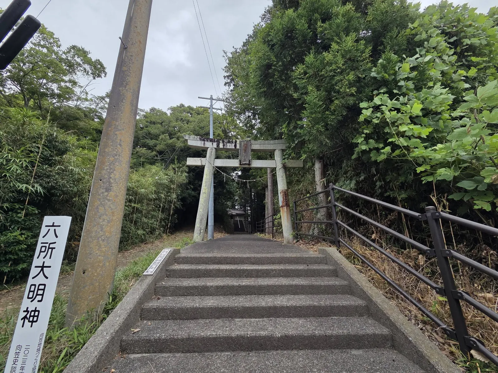 石段下から見る石造鳥居。右手に「六所大明神」の標柱が立つ。