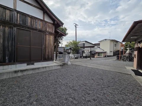 社殿を側面から見る。境内は砂利敷きで、前面道路に接する。
