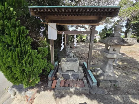参道脇の手水舎。石造りの水盤に柄杓が渡され、右奥に石灯籠が立つ。