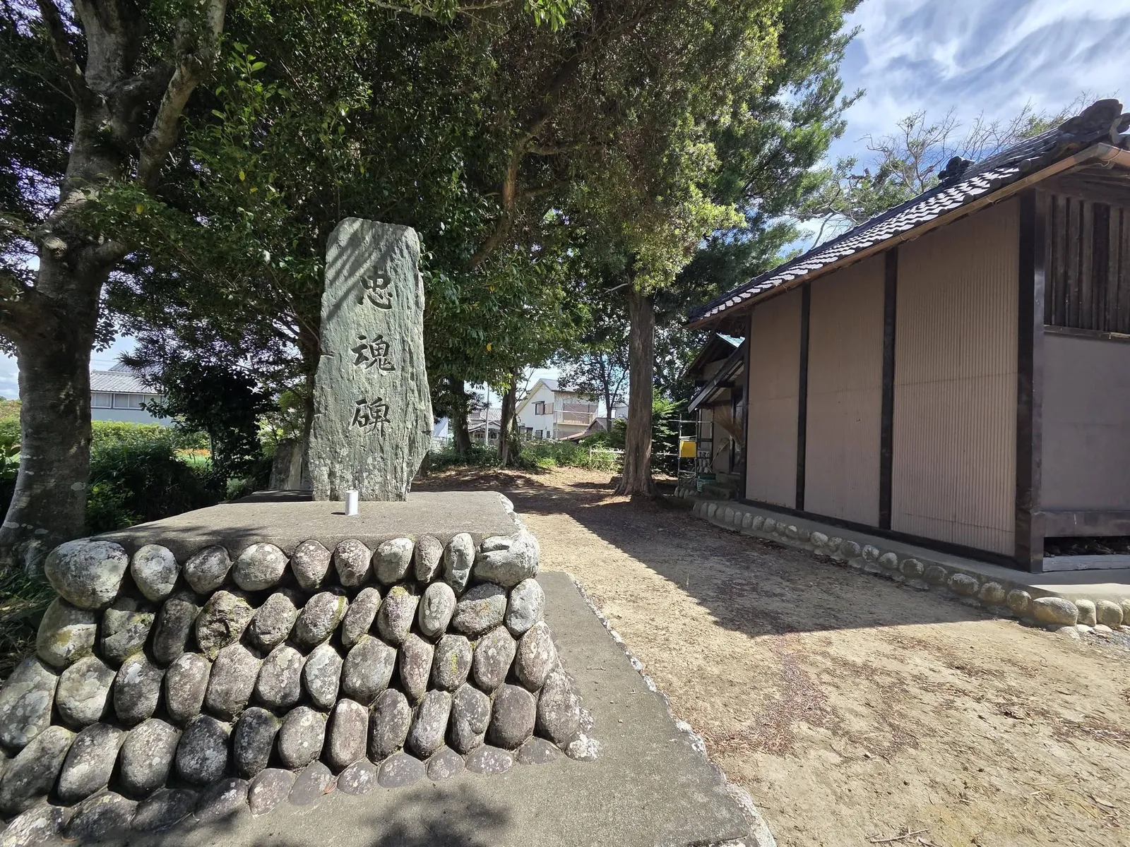 境内に立つ「忠魂碑」と刻まれた石碑。奥に瓦屋根の建物が見える。