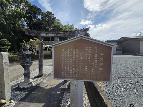 参道入口に立つ「須賀神社」の由緒板。祭神・例祭日・由緒を記す。奥に鳥居と灯籠が見える。