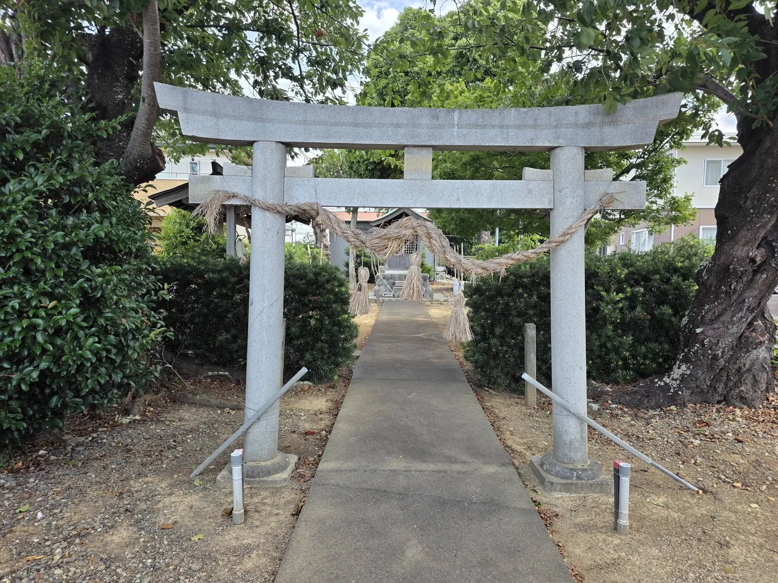 参道入口の石造鳥居。注連縄を張り、正面奥に社殿が見える。