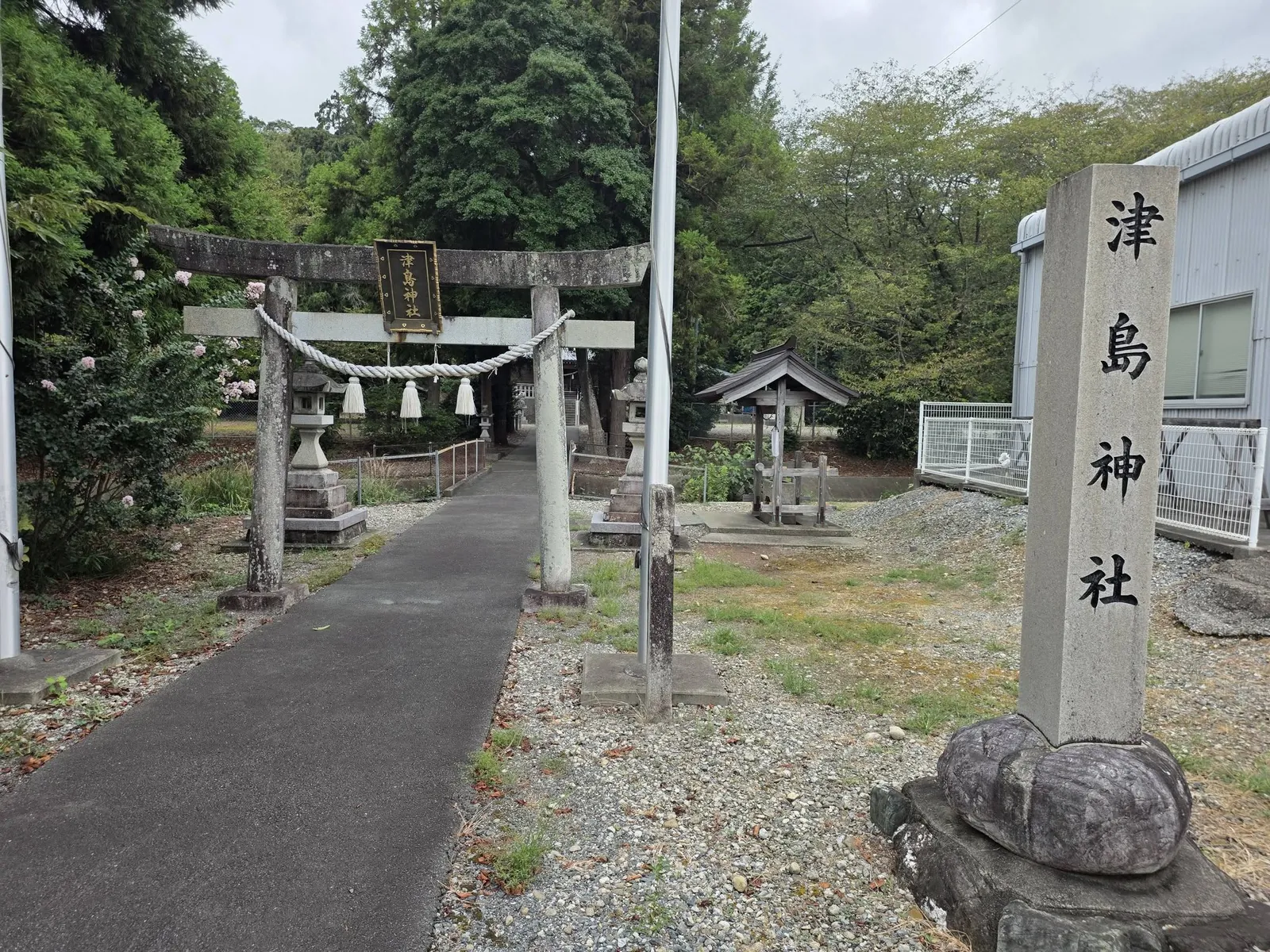 境内入口の石造鳥居と社号標。参道の先に社殿が見える。