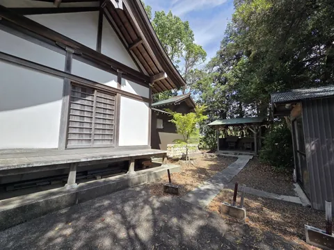 社殿の側面と境内の建物群。白壁の社殿と奥の境内社、附属の建物が木立の中に並ぶ。