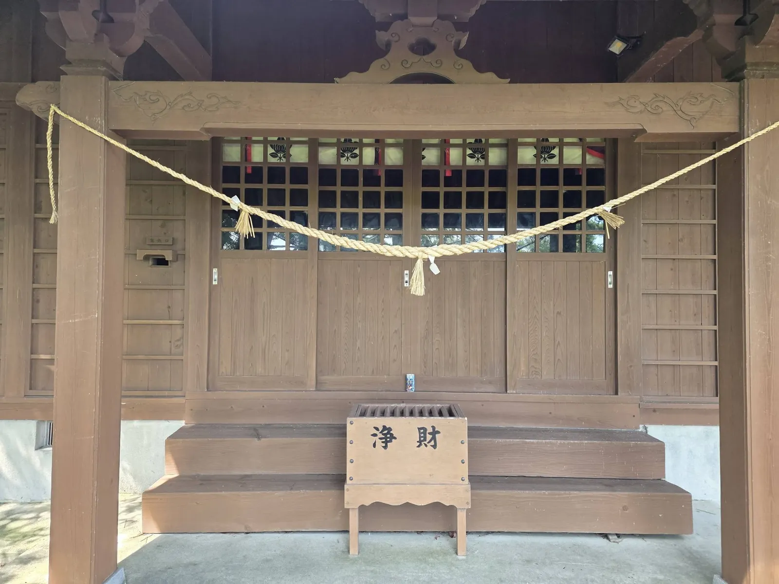 注連縄を張った社殿正面と賽銭箱。