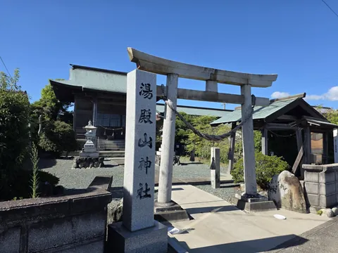 湯殿山神社：社号を刻む鳥居の柱と、奥に建つ湯殿山神社の社殿。
